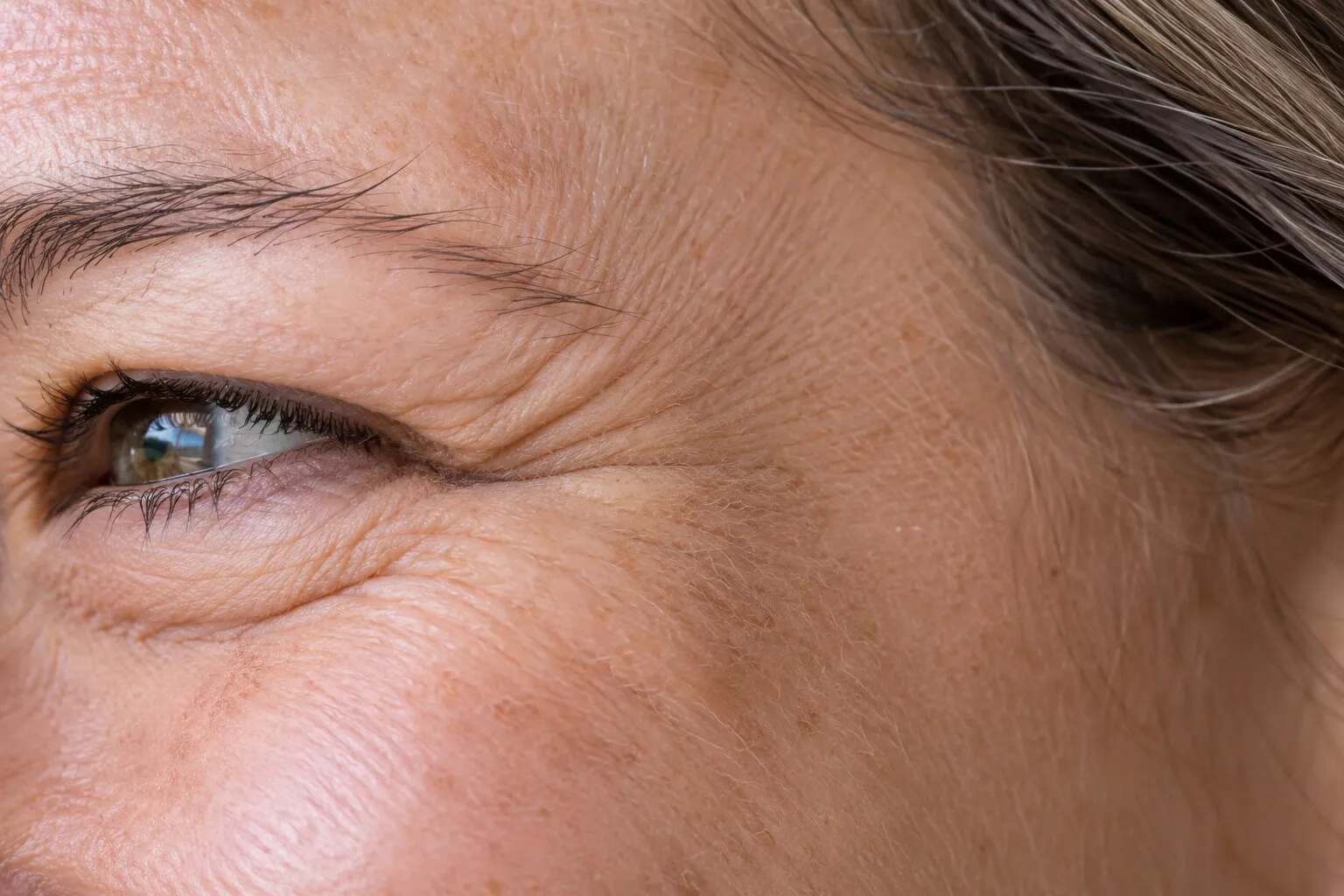 Close view of natural laugh lines at the outer corner of a smiling eye